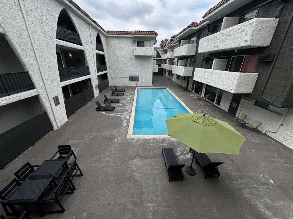 an outdoor patio with a pool and chairs and an umbrella