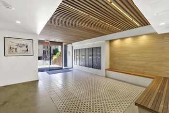 A hallway with a wooden ceiling and a bench on the right side.