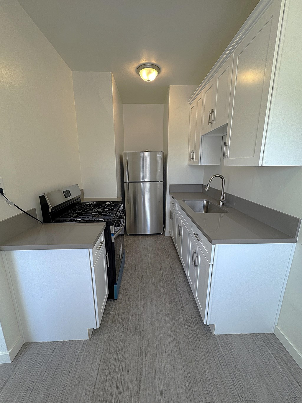 A kitchen with white cabinets and a stainless steel refrigerator.