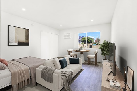 A bedroom with a bed, couch, and television.