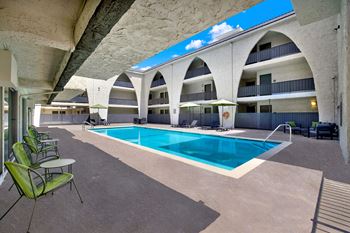 A large swimming pool is surrounded by chairs and tables.
