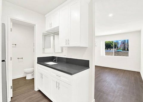 A kitchen with white cabinets and a black countertop.