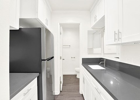 A kitchen with white cabinets and a black fridge.