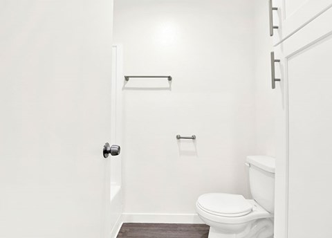 A white toilet sits in a bathroom next to a towel bar.