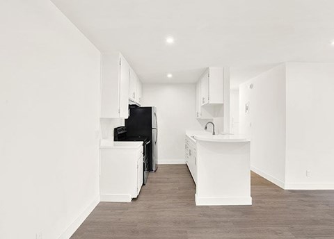 A kitchen with white cabinets and a black fridge.