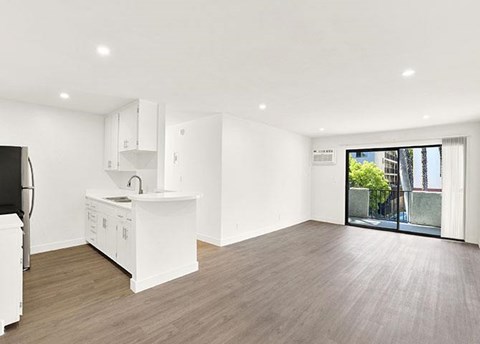 A kitchen with white cabinets and a wooden floor.