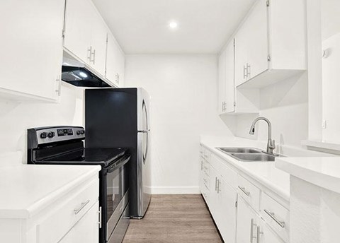 A kitchen with black appliances and white cabinets.