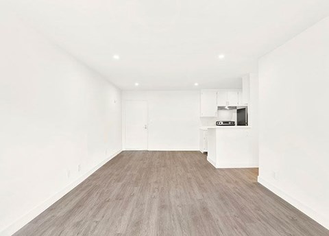 A spacious room with wooden flooring and white walls.