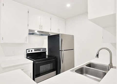 A black oven and fridge in a white kitchen.