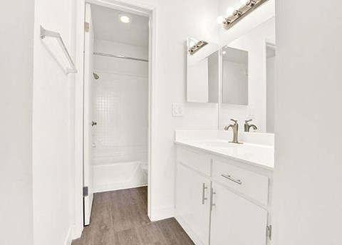 A white bathroom with a sink, mirror, and a shower.