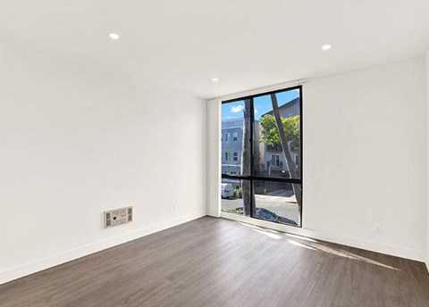 A room with a large window and wooden flooring.