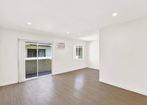 A room with a wooden floor and a doorway leading to a balcony.