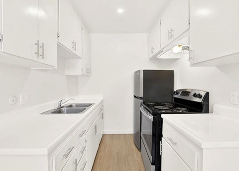 A white kitchen with a black stove top oven.