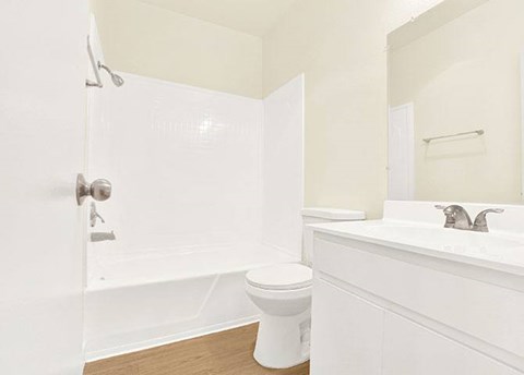A white bathroom with a toilet, sink, and shower.