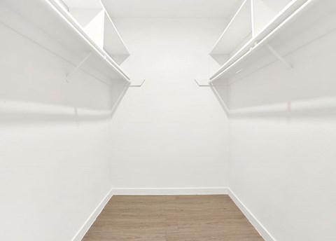 A white empty room with wooden flooring and white walls.