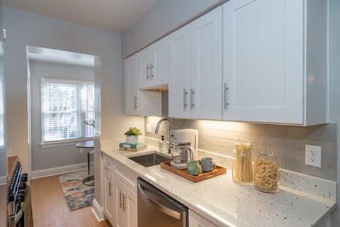 A kitchen with white cabinets and a marble countertop.