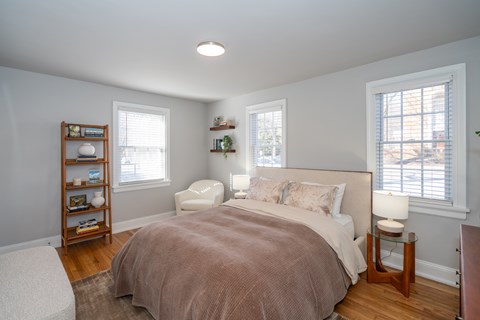 A bedroom with a bed, nightstand, and window.