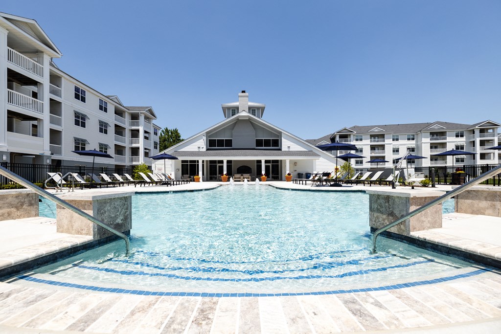 a large pool with chairs in front of an apartment building