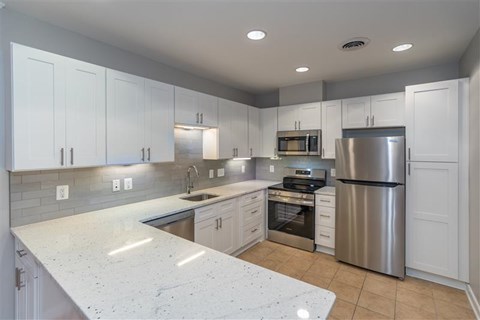 A kitchen with white cabinets and a marble countertop.