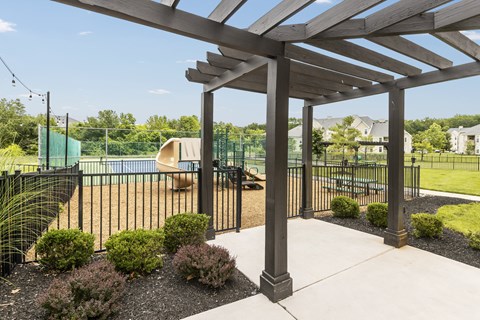 A tennis court is enclosed by a black fence and surrounded by green shrubbery.