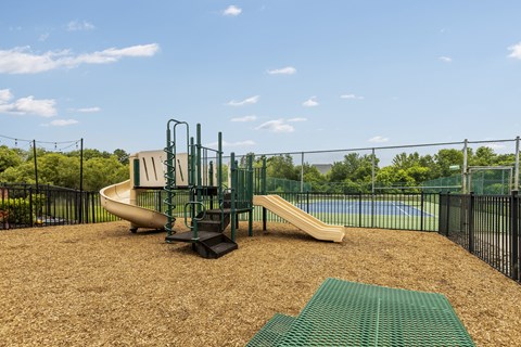 A playground with a slide and a green mat.