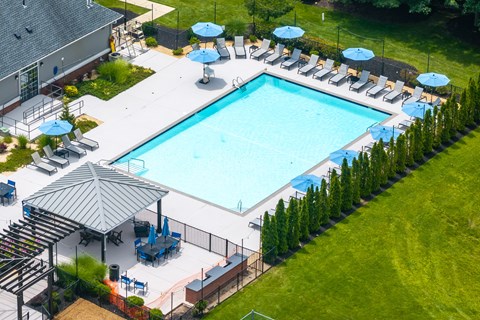 A large outdoor swimming pool surrounded by lawn chairs and umbrellas.