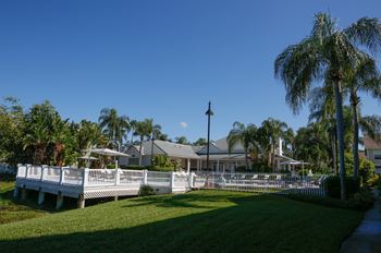 a white fence in front of a house with palm trees  at Champions Walk Apartment Homes, Florida