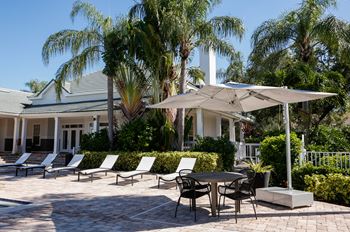 a patio with chairs and an umbrella in front of a house at Champions Walk Apartment Homes, Florida