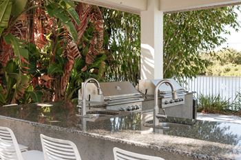an outdoor kitchen with a grill and a sink at Champions Walk Apartment Homes, Florida, 34210