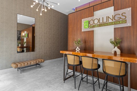 A conference room with a wooden table and chairs, a mirror, and a sign that reads "COLLINGS at the LUMBERYARD".