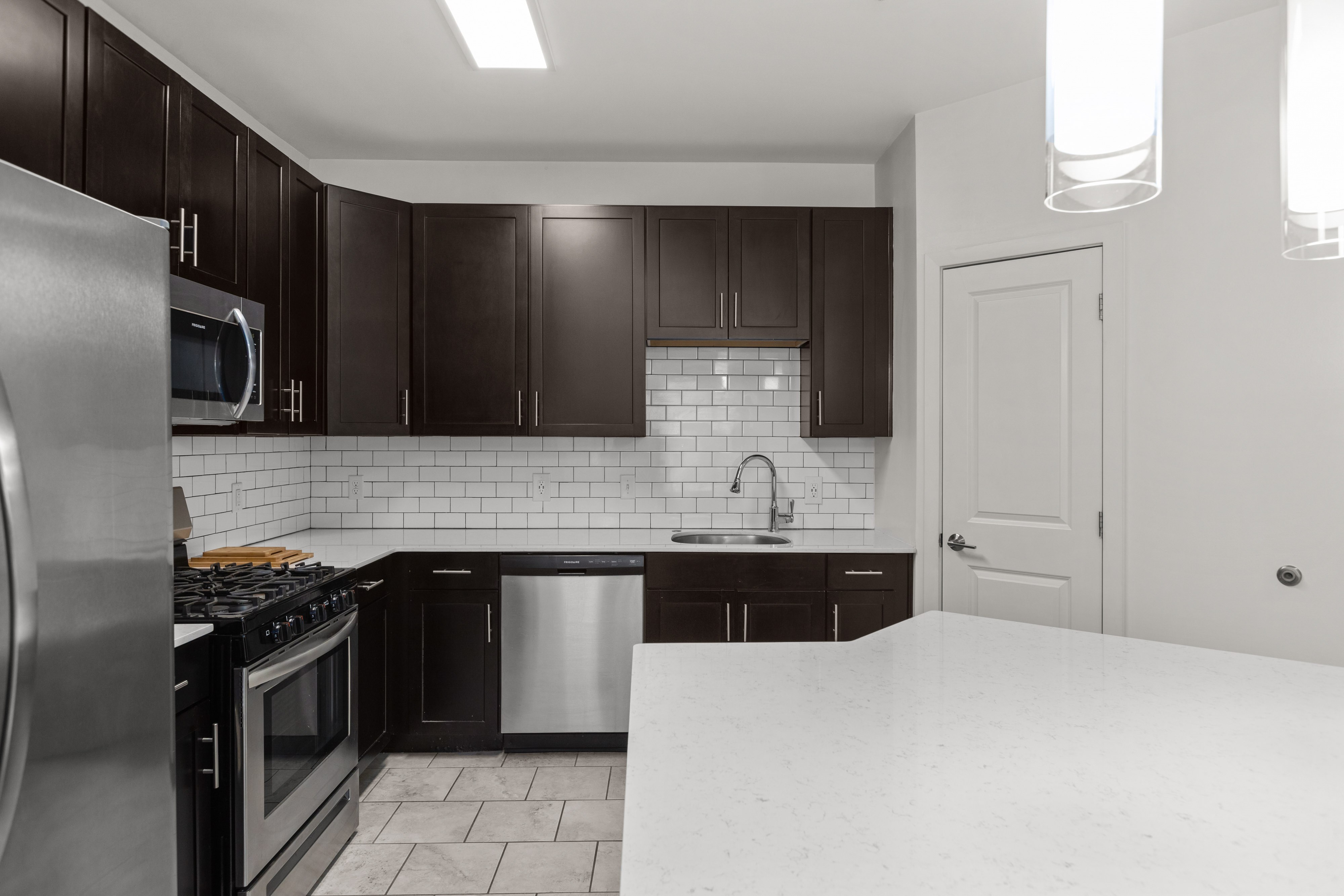 A kitchen with black cabinets and a white countertop.