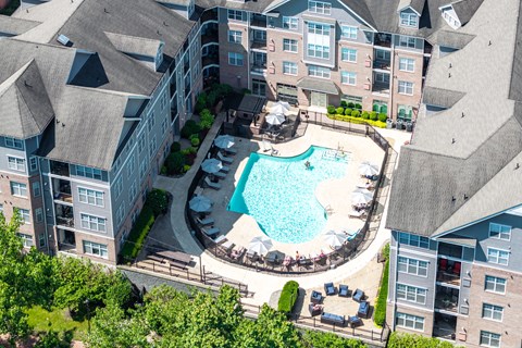An aerial view of a pool surrounded by buildings and trees.