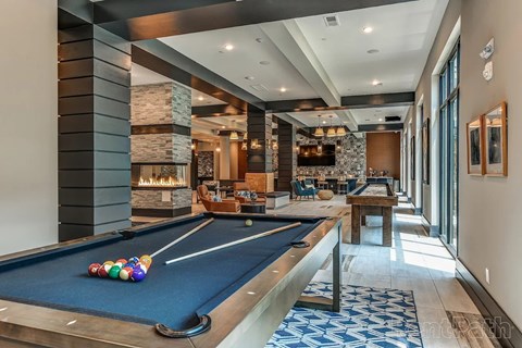 A pool table is in the middle of a room with a fireplace and a couch.