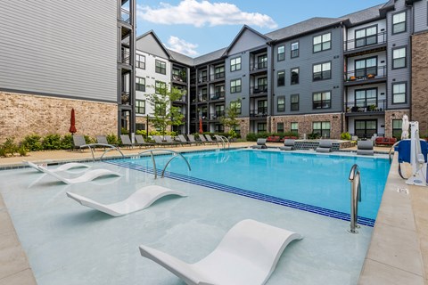 A swimming pool with lounge chairs and a building in the background.