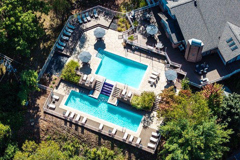 An aerial view of a pool surrounded by trees and a house.