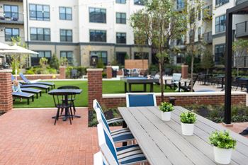 a patio with a wooden table and chairs in front of an apartment building at The Yards at Malvern, Malvern, PA, 19355