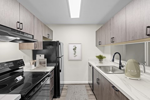 A kitchen with black appliances and wooden cabinets.