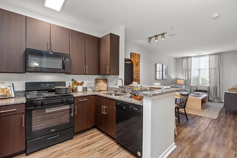 A kitchen with dark wood cabinets and a black oven.
