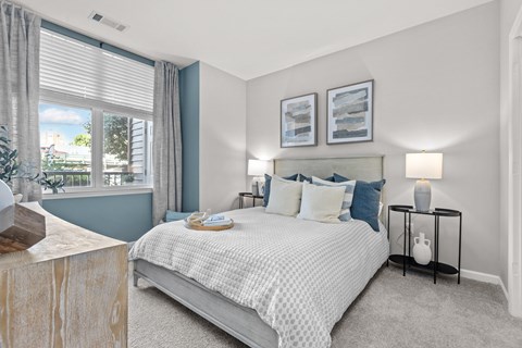 A bedroom with a large bed and a window with curtains.