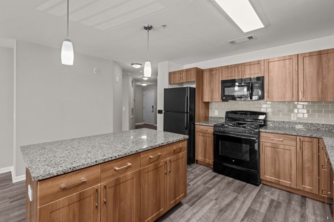 A kitchen with wooden cabinets and a black refrigerator.