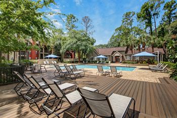 a swimming pool with chairs and tables on a wooden deck at Timberwalk at Mandarin Apartment Homes, Florida, 32257