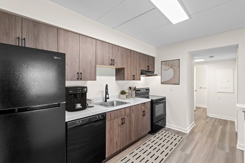Modern kitchen with black appliances and wood cabinets at The Crossings at Halfmoon Apartments, Clifton Park, NY