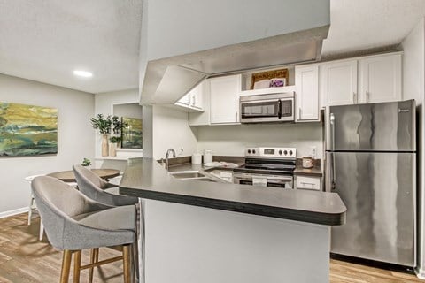 a kitchen with stainless steel appliances and a counter with chairs at Timberwalk at Mandarin Apartment Homes, Florida, 32257