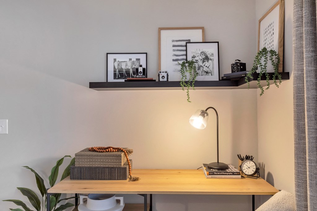 a desk with a lamp and pictures on a shelf above it at The Austin Apartment Homes, Deptford