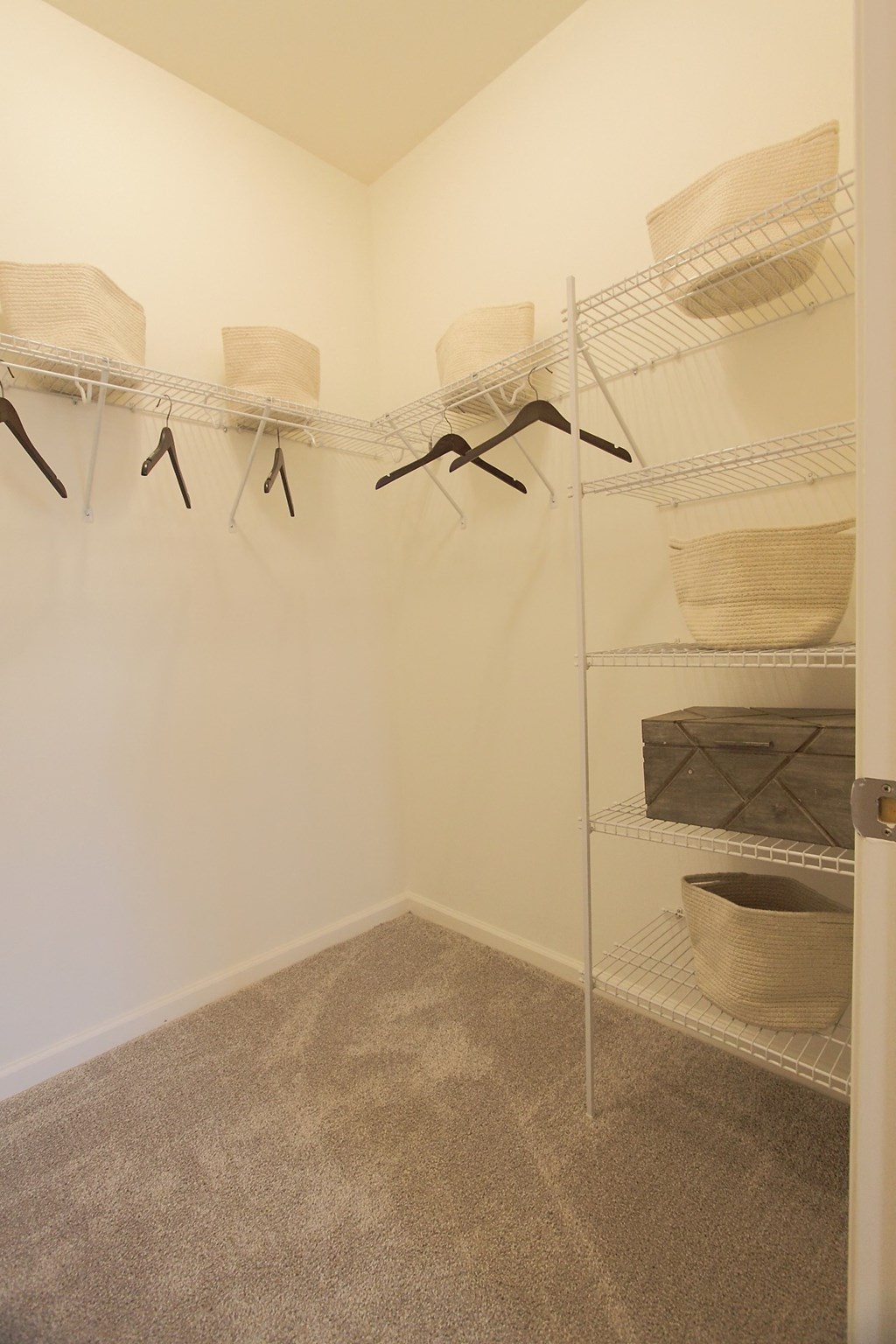 a closet with shelves and baskets in a room with carpet and white walls  at Carillon Woods, Millsboro, Delaware