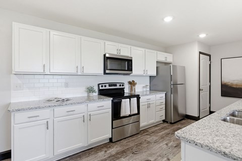 A modern kitchen with white cabinets and stainless steel appliances.