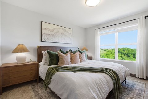 A bedroom with a large bed, a lamp, and a painting on the wall.