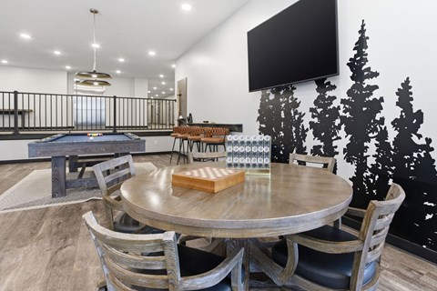 A modern dining room with a pool table and a television mounted on the wall.