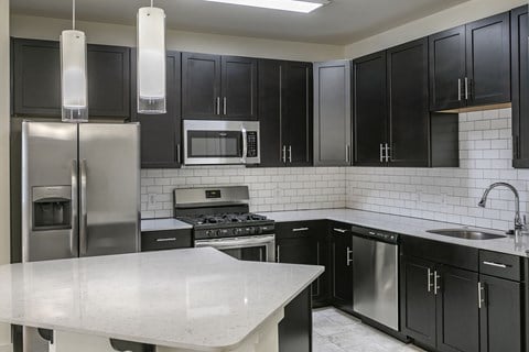 a modern kitchen with stainless steel appliances and black cabinets at The Collings at Lumberyard