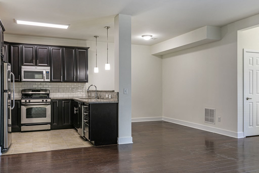 an empty kitchen with black cabinets and stainless steel appliances at The Collings at Lumberyard